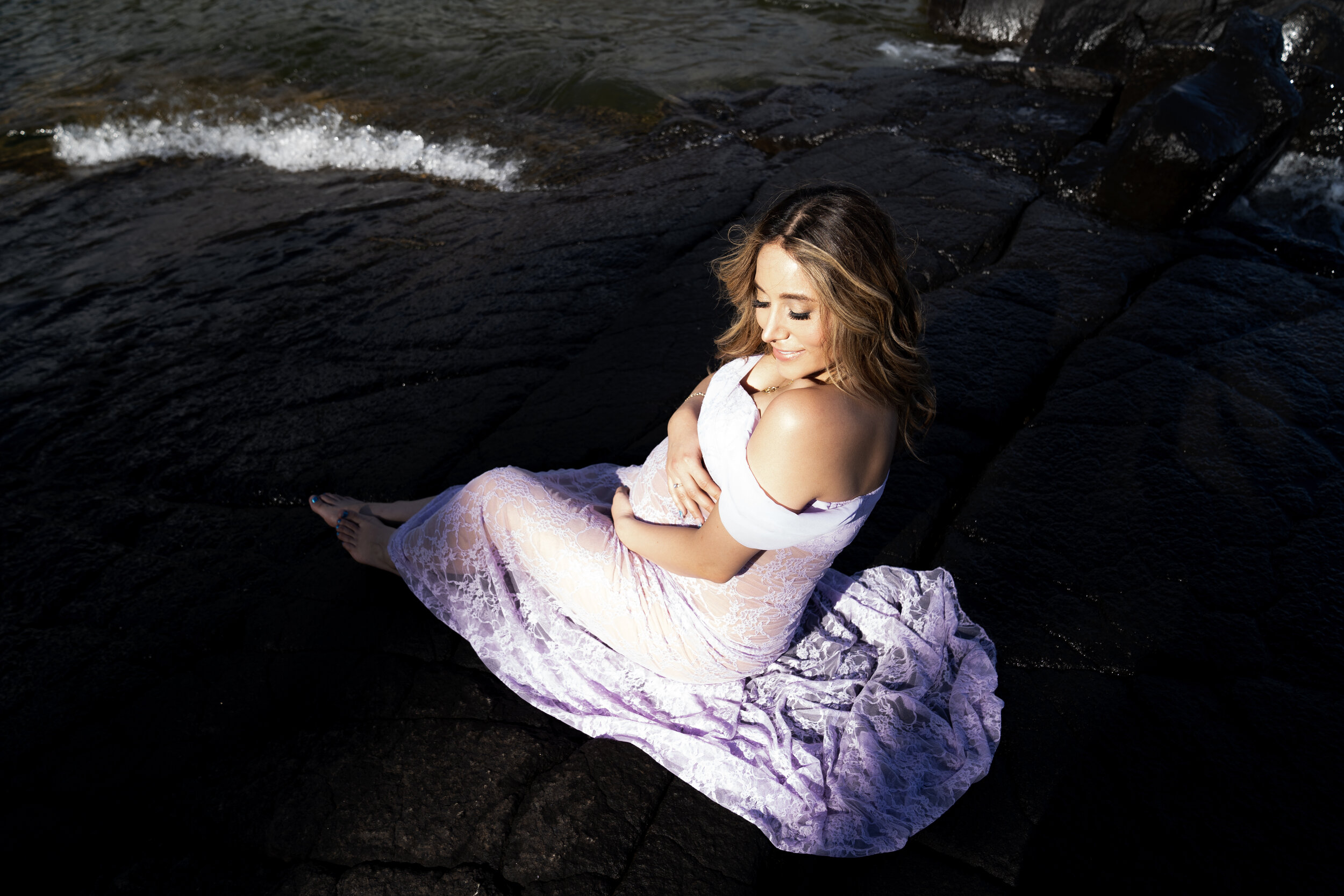 Pregnant woman in a lilac gown holding her belly - image taken from above