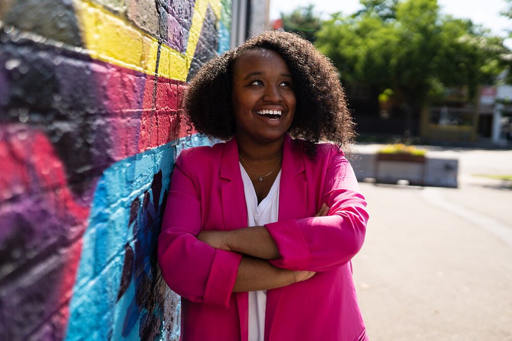 black women in hot pink blazer next to graffiti wall