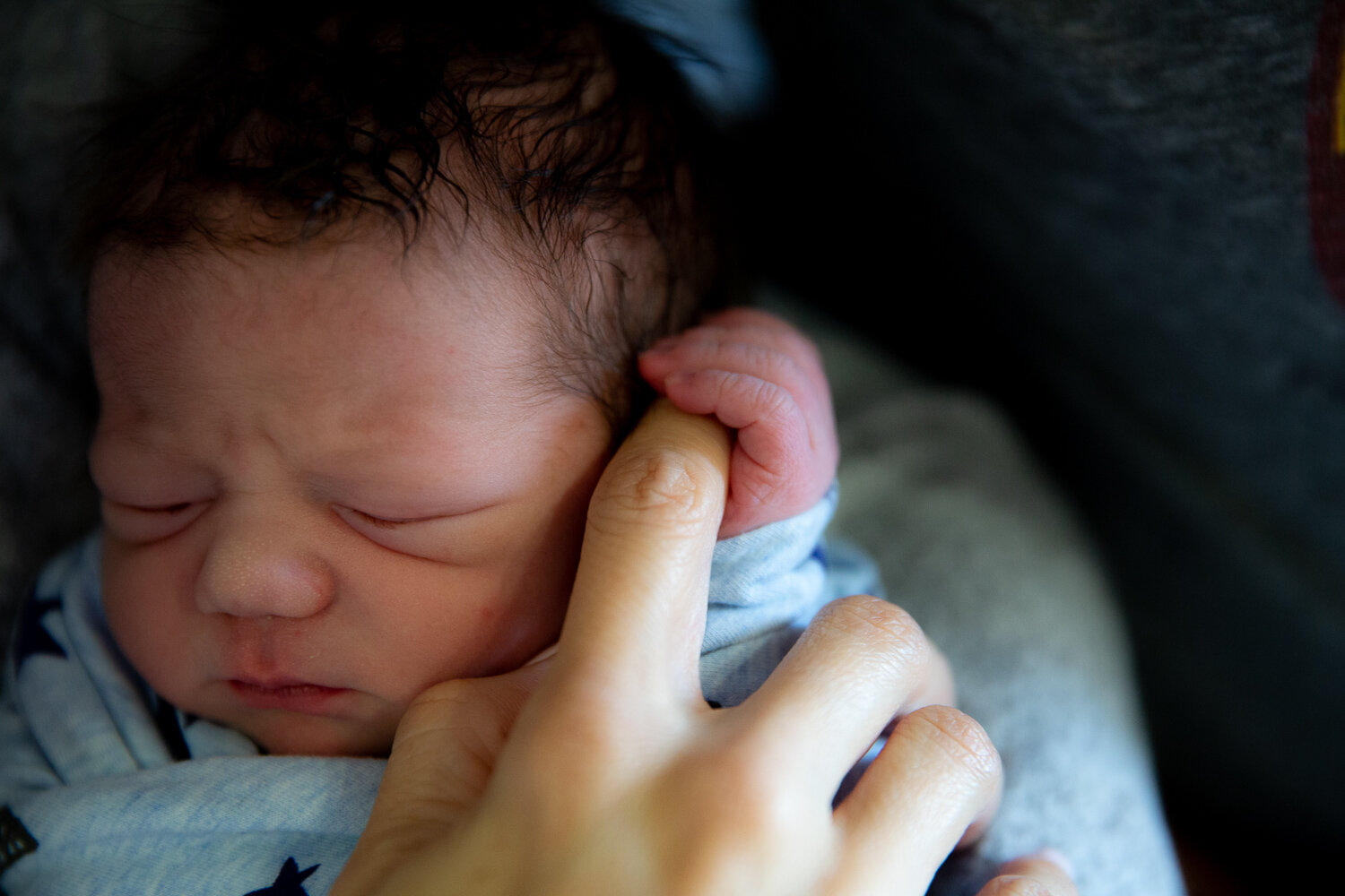 Newborn baby holding onto mom's finger during a fresh 48 session