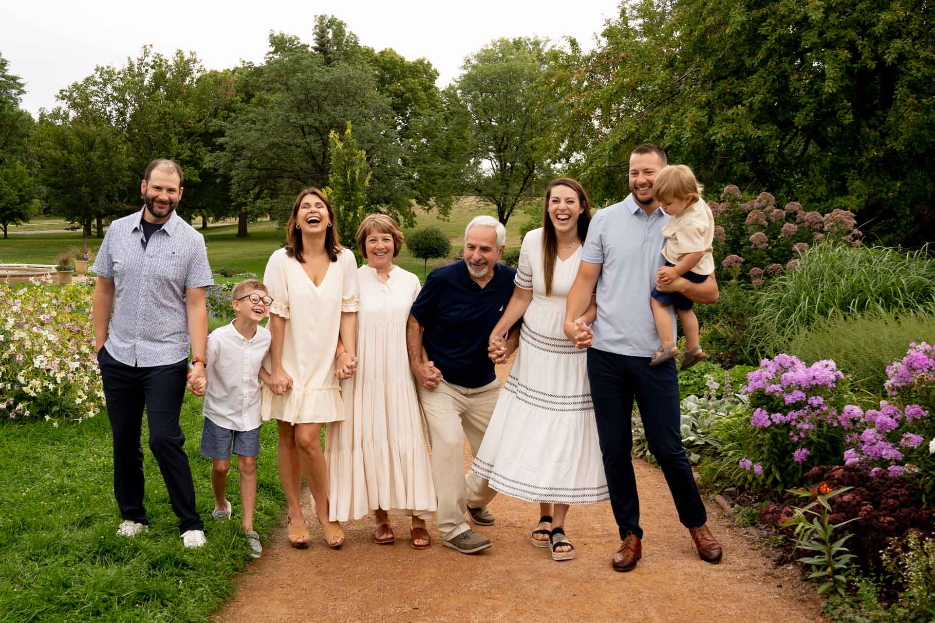 Large family dressed in neutral tones posed in a botanical garden for family photos