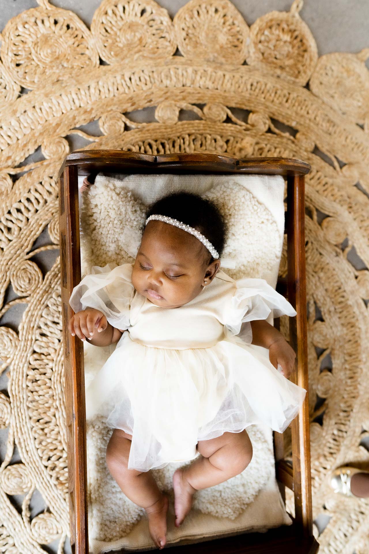 Wiggly baby posed in a wooden crib for newborn photography