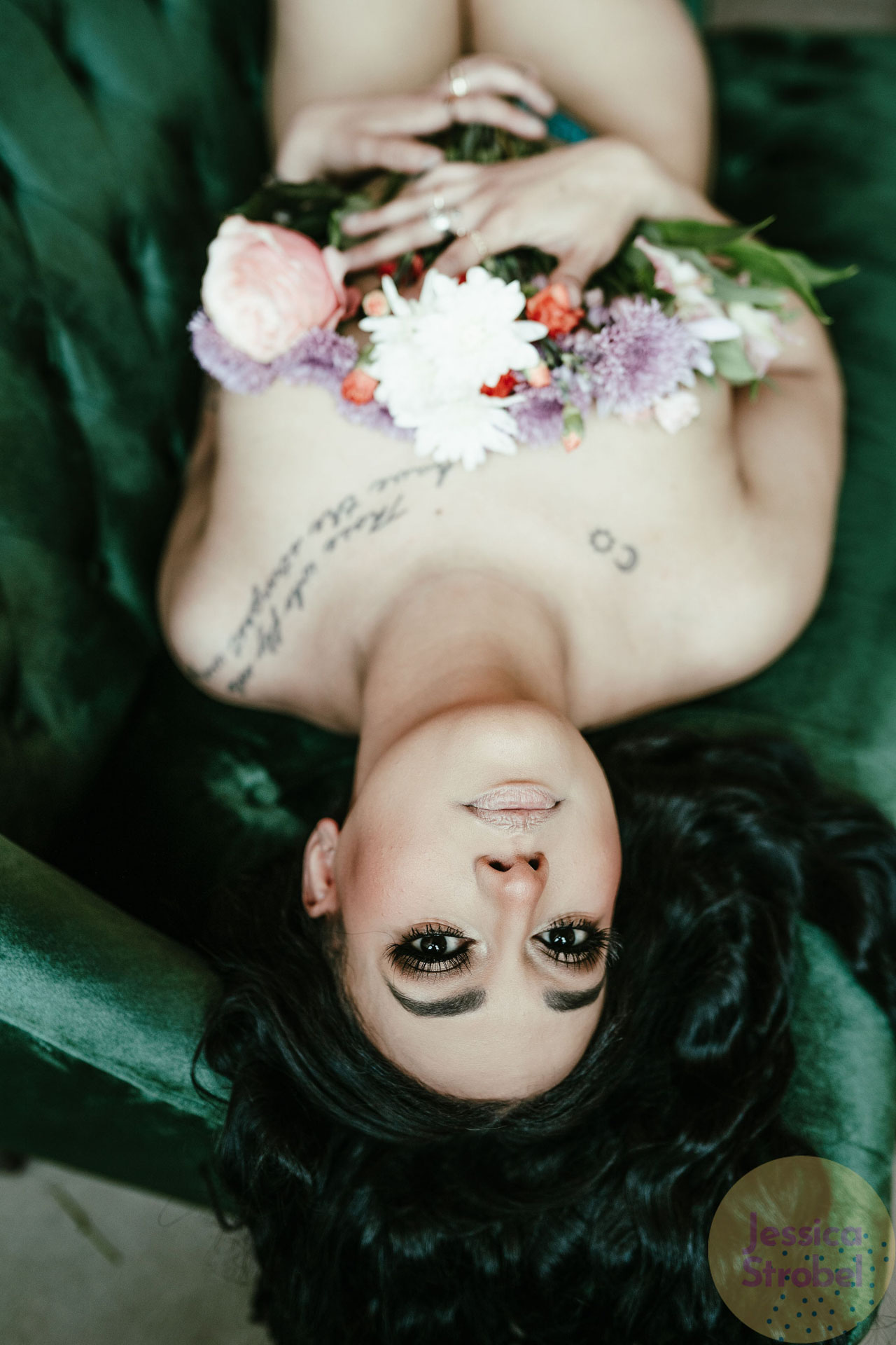 women laying on green velvet couch with fresh flowers covering her breasts