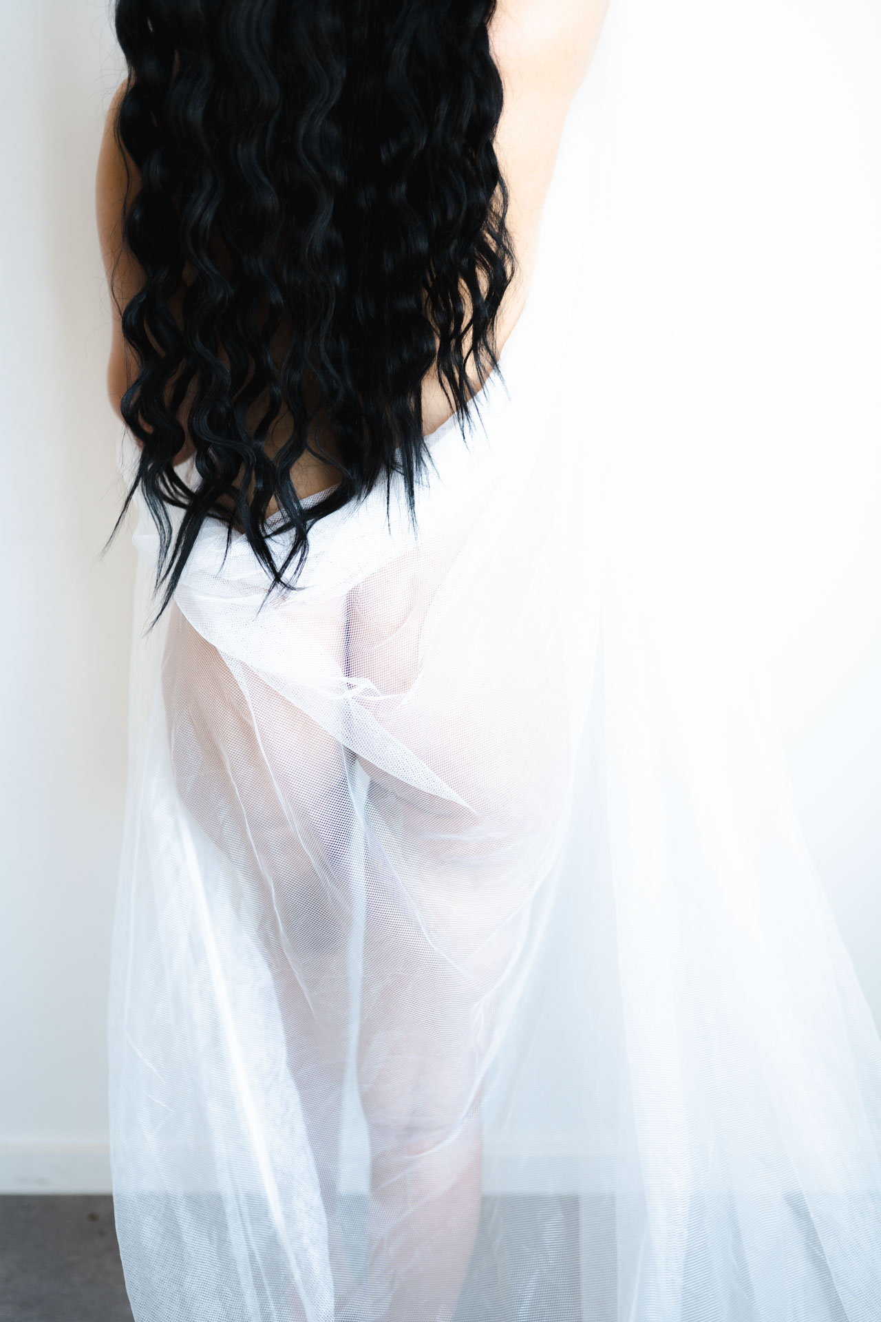 sheer white curtain cover buttocks and legs of woman with hair coming down to brown her waist