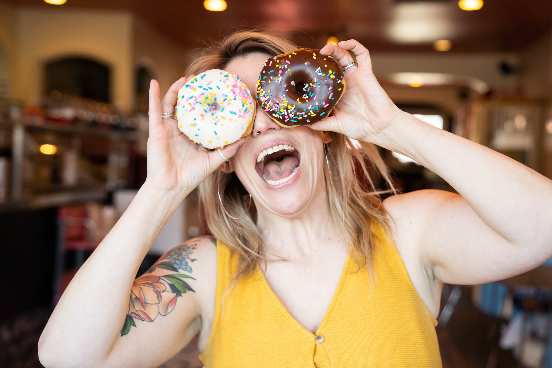 Jessica Strobel holding multi-colored doughnuts over her eyes, smiling wide