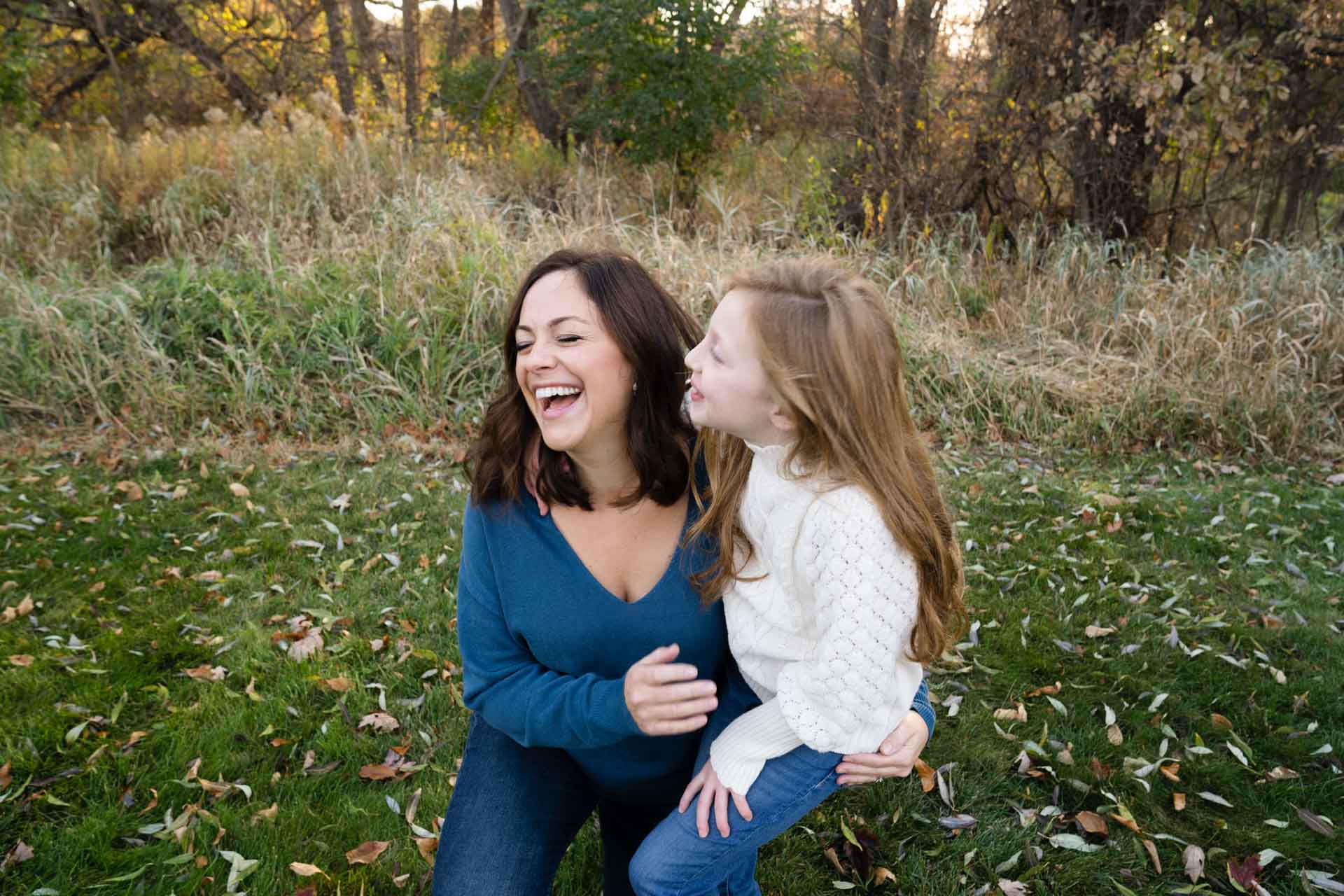 mom and daughter laughing and smiling wearing blue and white during a fall photo session