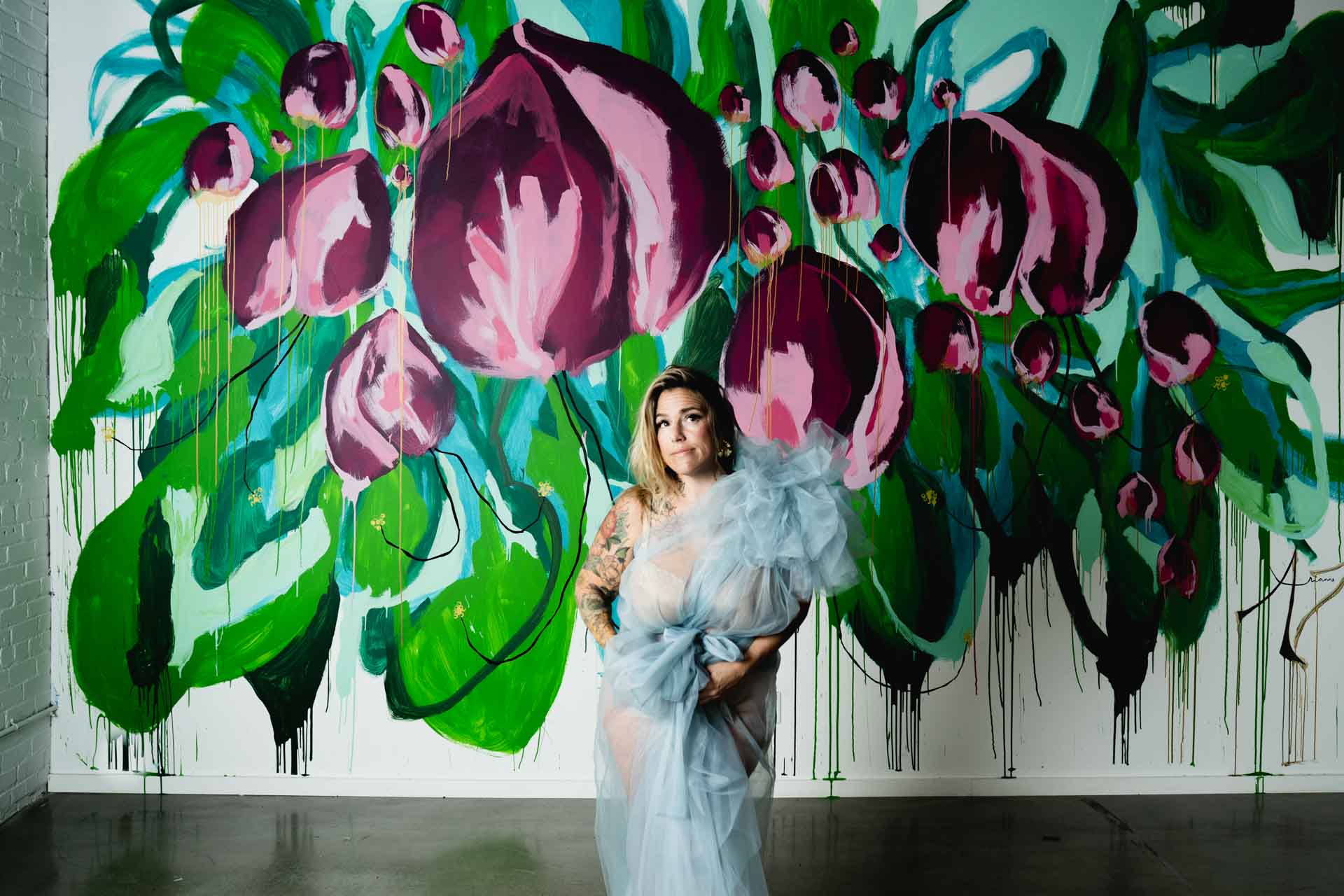 Jessica Strobel in a gown posed in front of a vibrant floral mural