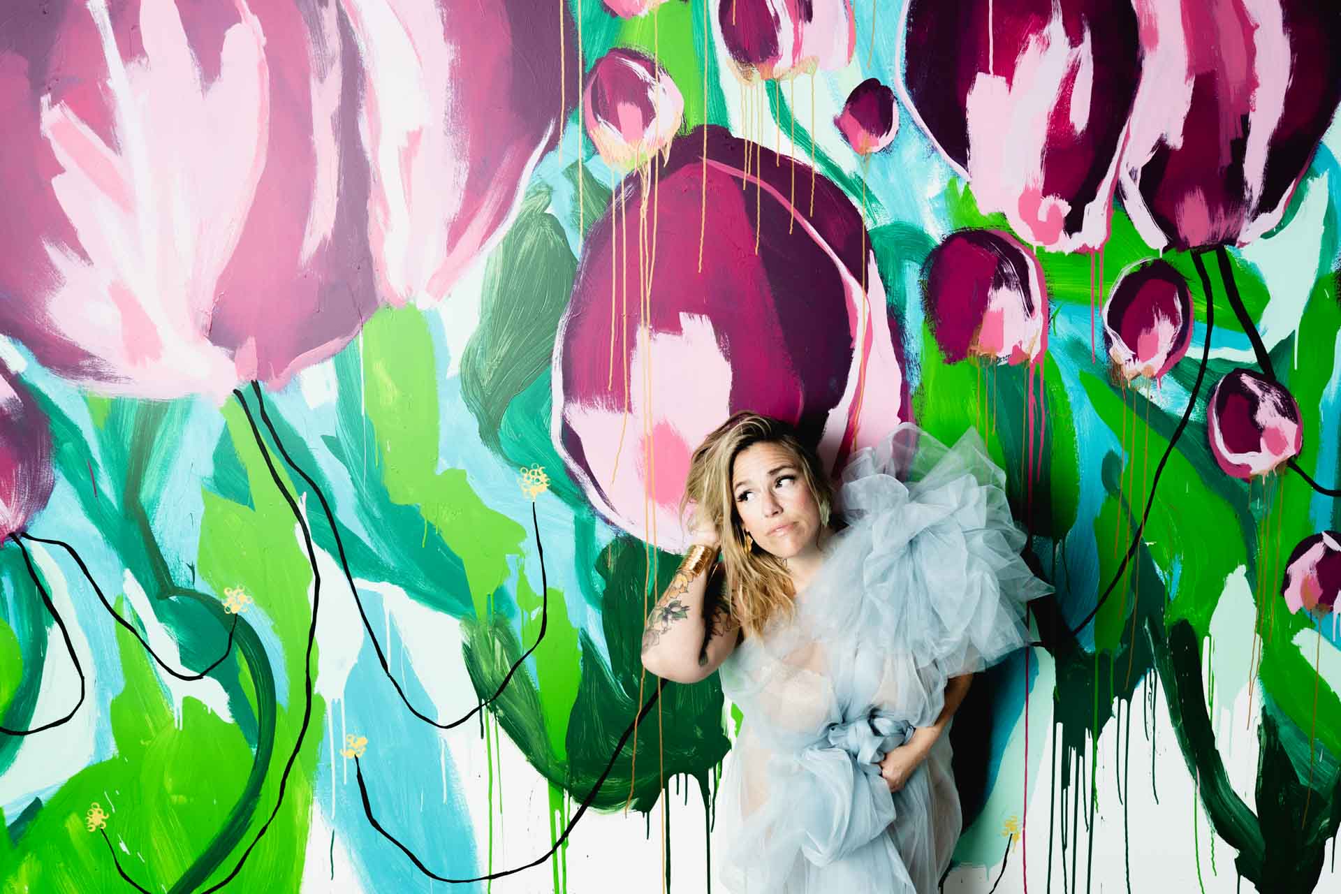 Jessica Strobel in a gown posed in front of a vibrant floral mural