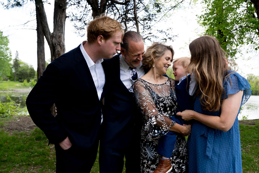 grandparents, parents, and a young boy posed together artistically while laughing at a Minneapolis anniversary party