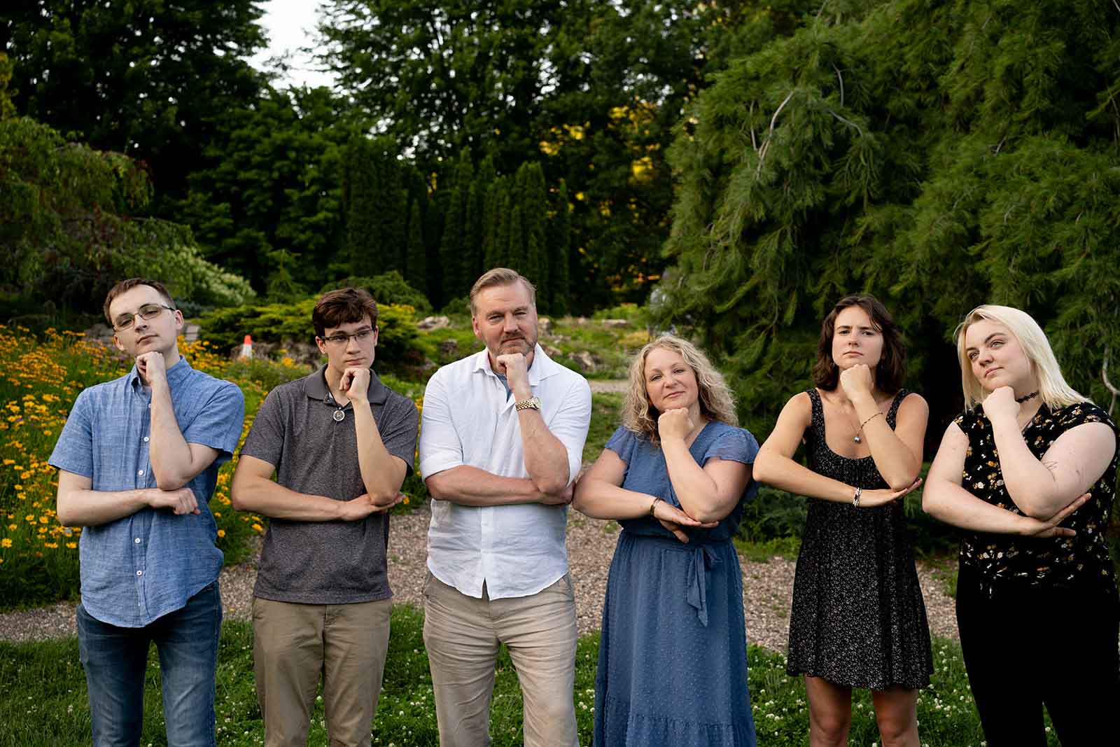 a family of six posing with their arms on an imaginary table while laughing together during a Minneapolis family photo session