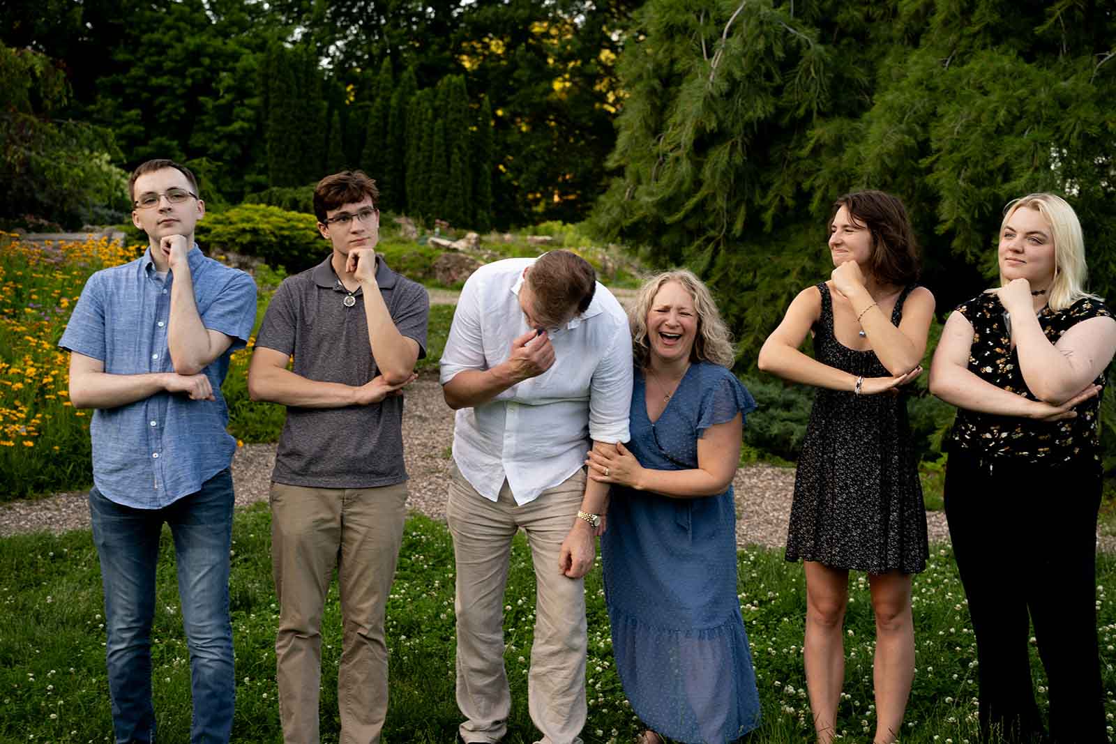 a family of six posing with their arms on an imaginary table while laughing together during a Minneapolis family photo session