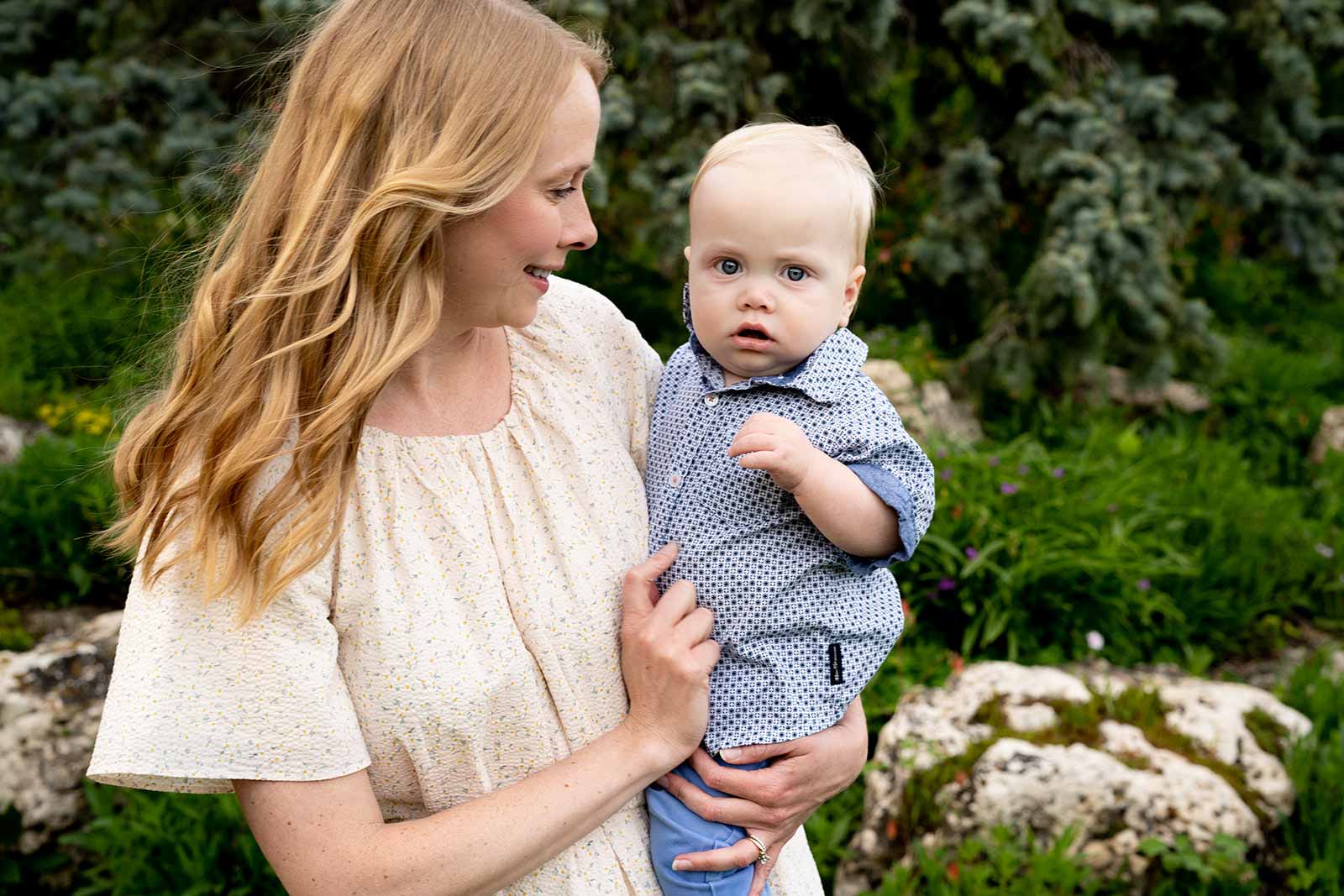 A mother looking emotionally at her toddler son while she holds him on her hip, and he looks intently into the camera