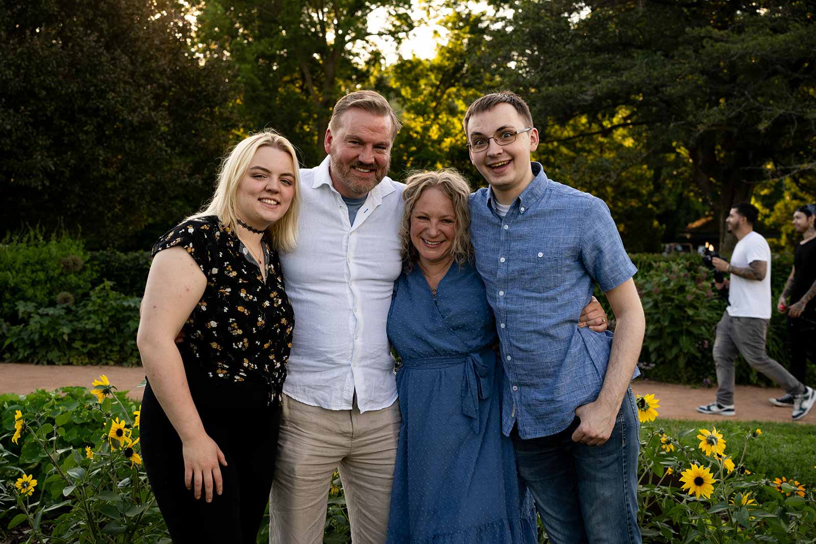 a family of four standing together in a Minneapolis metropark, smiling and making silly faces into the camera