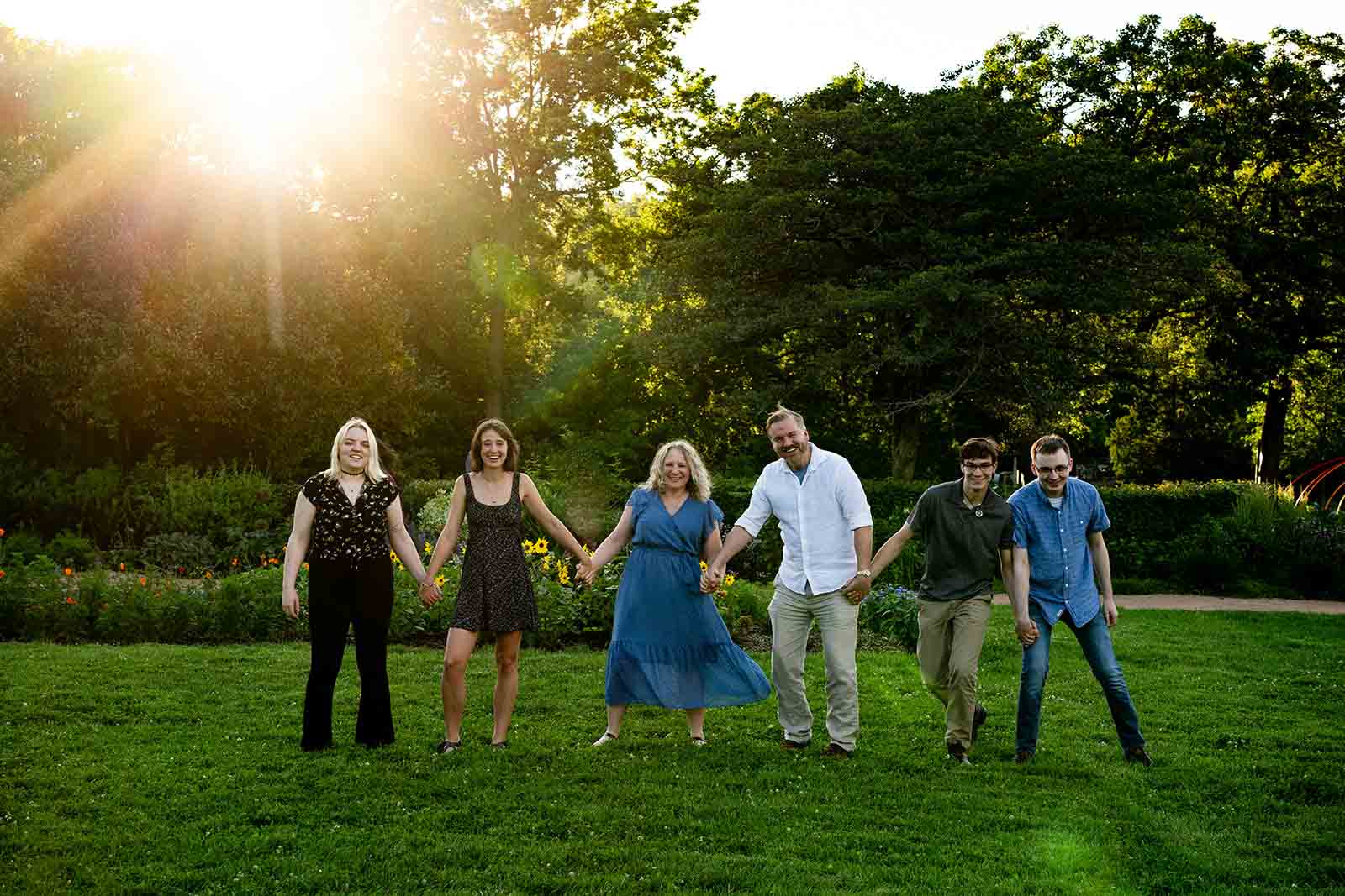 family of six holding hands and walking toward the camera at a golden hour family photo session