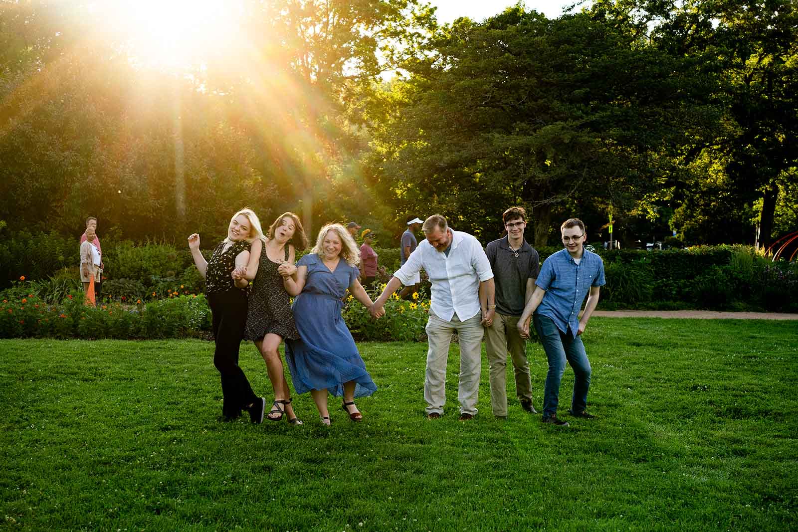 family of six holding hands and walking toward the camera at a golden hour family photo session