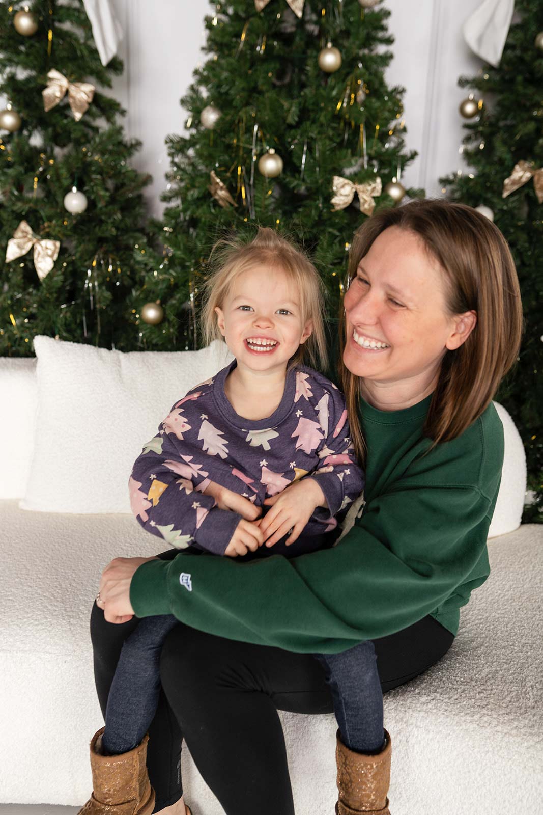 two kids sitting on a green velvet couch with Santa Claus during a Christmas photo session